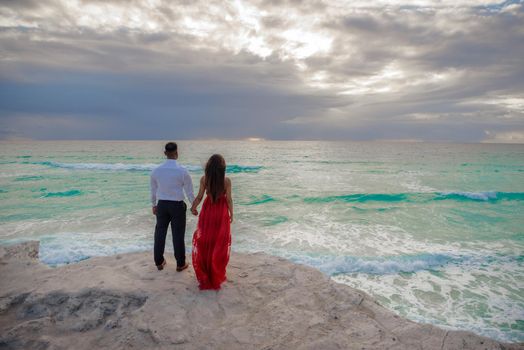 A man and a woman walk on the seashore.