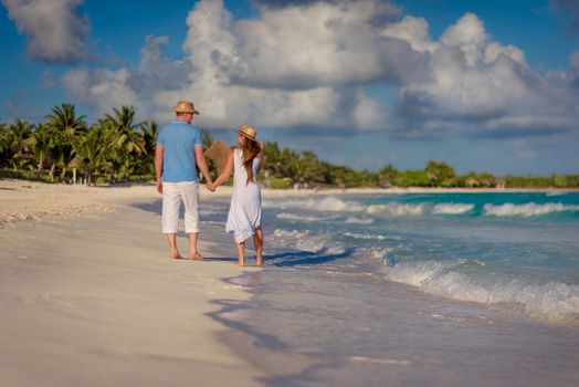 A man and a woman walk on the seashore.