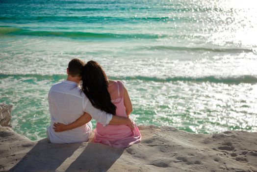 A man and a woman are sitting on the seashore.