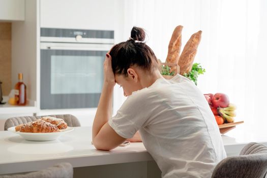 Young sad woman suffering in kitchen, Stressed housewife in a kitchen