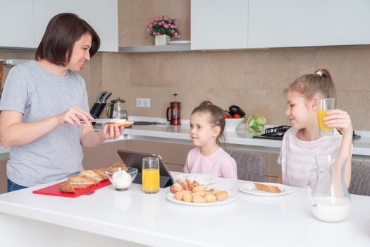 Mother and two daughters having breakfast together, happy single mother concept