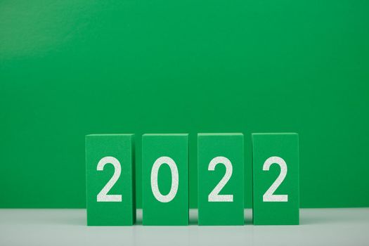 2022 numbers on white table against green background with copy space. Minimal elegant concept of New Year celebration