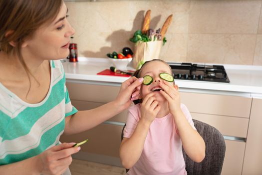 Happy young mother and daughter having fun in kitchen