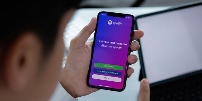 CHIANG MAI, THAILAND - APR 06, 2021: Person holding a brand new Apple iPhone XS with Spotify logo on the screen. Spotify is a popular commercial music streaming service.
