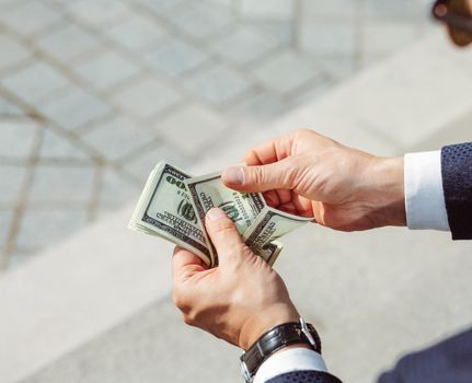 Men's hands hold dollars. Successful businessman considers salary.Male arms with watch, close up shot. High quality photo.