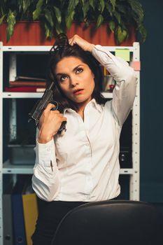 Crazy business woman with gun in office. Young Caucasian woman has problems. Suicide concept. Frustration concept. Toned image.