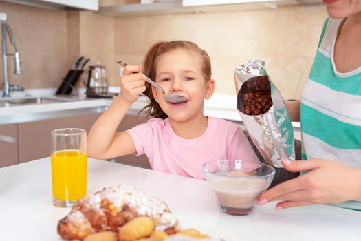 Mother serving breakfast to her two daughters at a table in kitchen