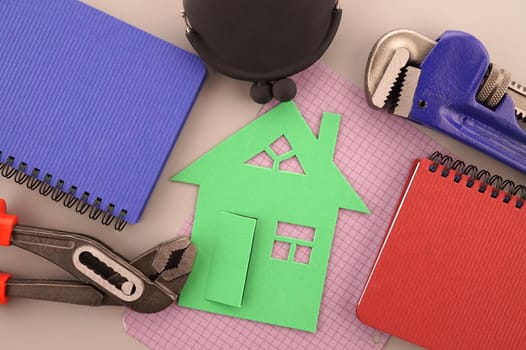 House ownership, building or construction still life concept with a flat lay of notebooks, wrench, purse, pencil and colorful cutout paper homes