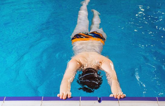 Preteen boy swimming and training in a pool