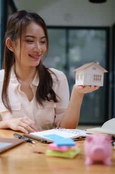 A real estate agent demonstrates the House model to clients interested in purchasing house insurance. The concept of home insurance and property