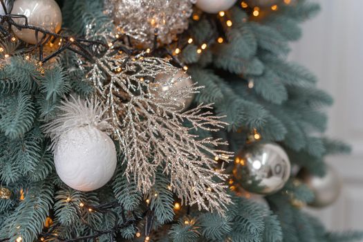 New Year's Tree close-up. Christmas tree branches are decorated with balloons and garlands. Silver branches decorate the tree. High quality photo.