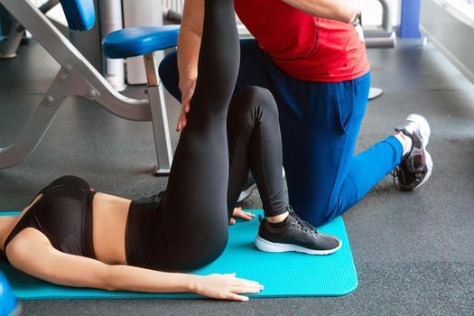 personal trainer man helping young woman in modern gym