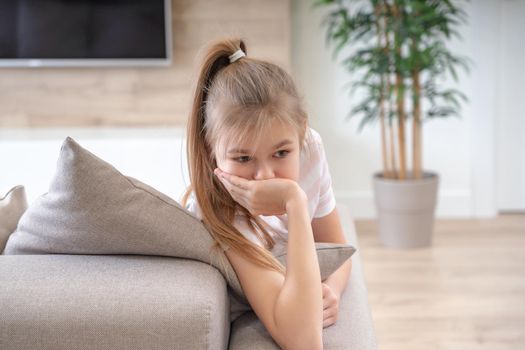 A little girl sitting on a couch. High quality photo