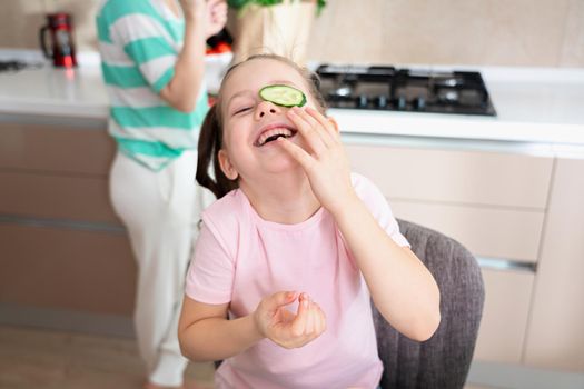 Happy young mother and daughter having fun in kitchen