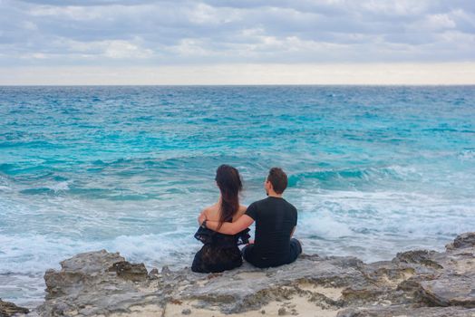 A man and a woman are sitting on the seashore.