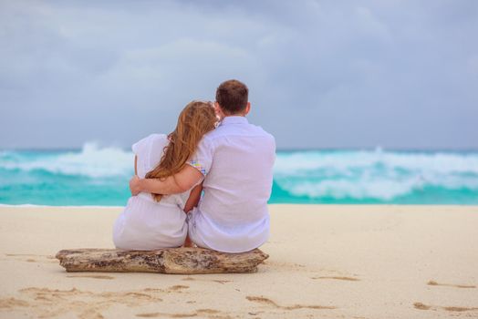 A man and a woman are sitting on the seashore.