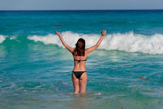 A woman on the beach looks at the horizon and walks along the beach. Mexico.