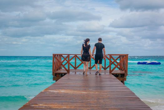 A man and a woman walk on the pier by the sea.