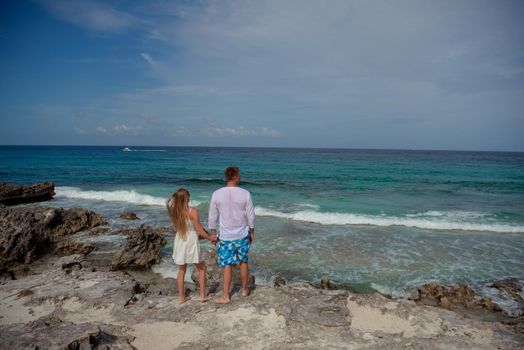 A man and a woman walk on the seashore.