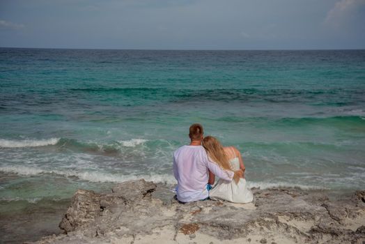 A man and a woman are sitting on the seashore.