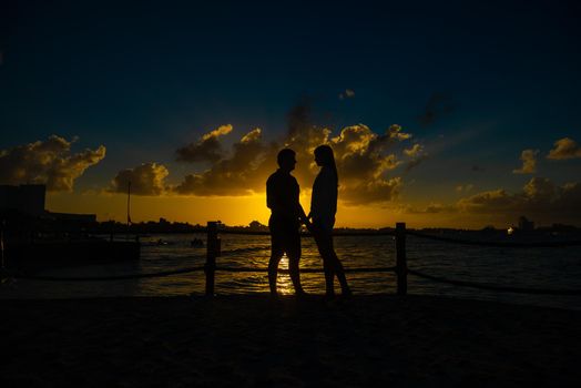 Silhouettes of men and women against the backdrop of the setting sun. Mexico.