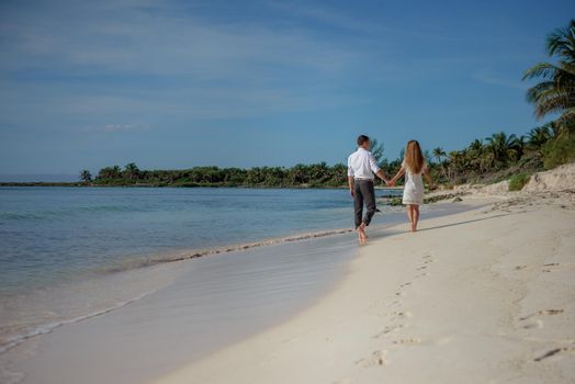 A man and a woman walk on the seashore.