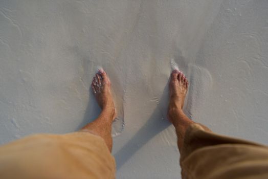 Female legs on sandy beach with seaweed.