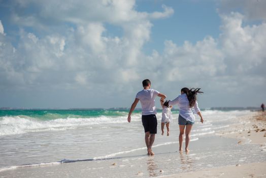 Parents with a small child walk on the beach and admire the horizon. Mexico..