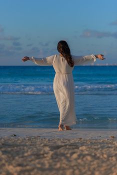 A woman on the beach looks at the horizon and walks along the beach. Mexico.