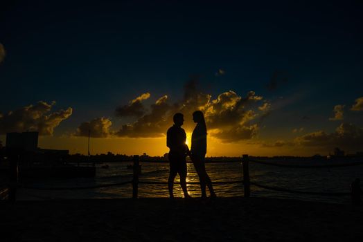 Silhouettes of men and women against the backdrop of the setting sun. Mexico.