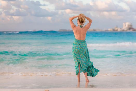 A woman on the beach looks at the horizon and walks along the beach. Mexico.