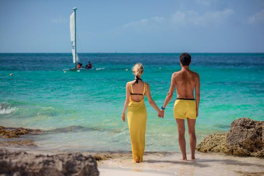 A man and a woman walk on the seashore.