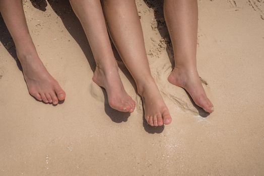 Feet of man and woman in the sand.