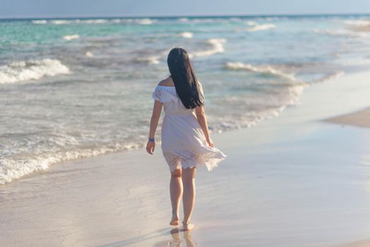 A woman on the beach looks at the horizon and walks along the beach. Mexico.