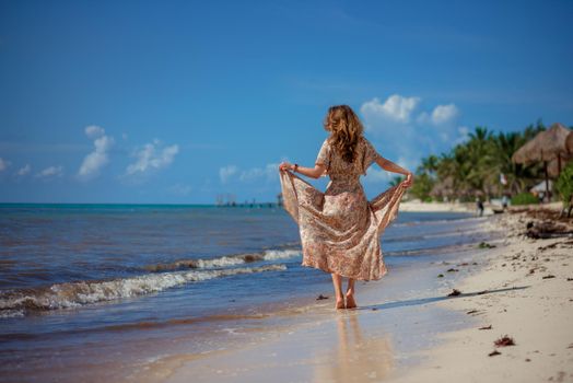 A woman on the beach looks at the horizon and walks along the beach. Mexico.