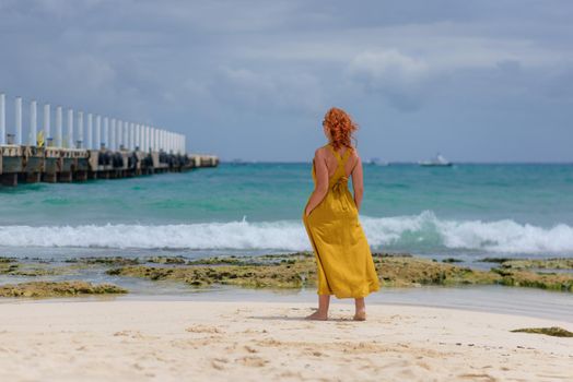 A woman on the beach looks at the horizon and walks along the beach. Mexico.