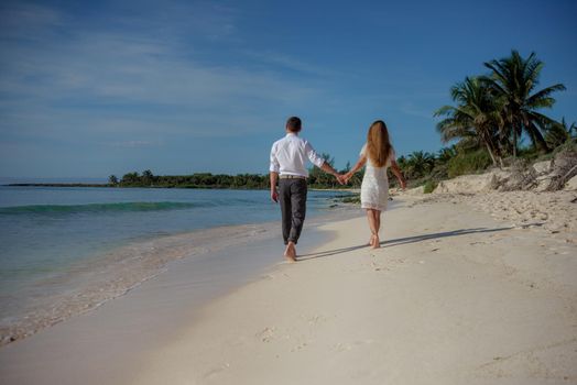 A man and a woman walk on the seashore.