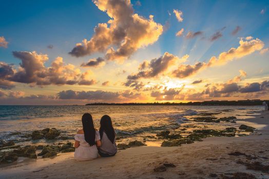 Silhouettes of two women against backdrop of the setting sun