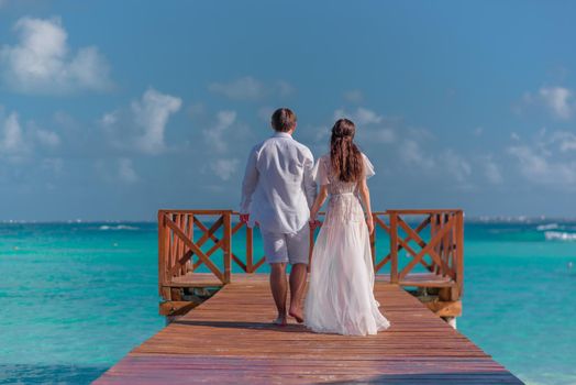 A man and a woman walk on the pier by the sea.