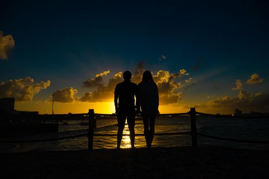 Silhouettes of men and women against the backdrop of the setting sun. Mexico.