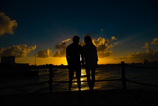 Silhouettes of men and women against the backdrop of the setting sun. Mexico.