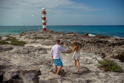 A man and a woman walk on the seashore.