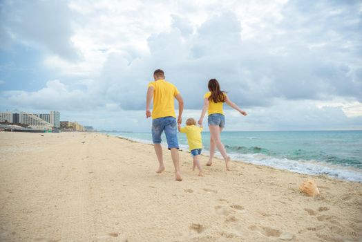 Silhouette of a family holding hands on the beach at sunset with azure sea