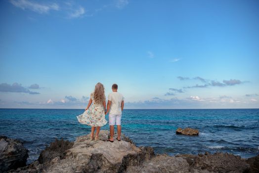 A man and a woman walk on the seashore.