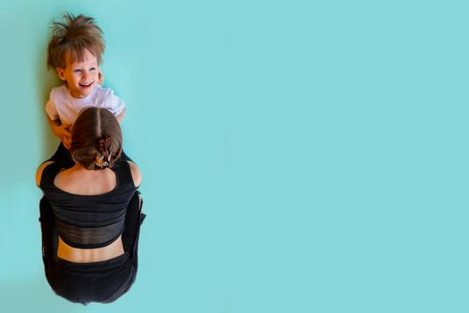 family sport. mother teaches son to do yoga. Helps with stretching. On the balcony In a home apartment.