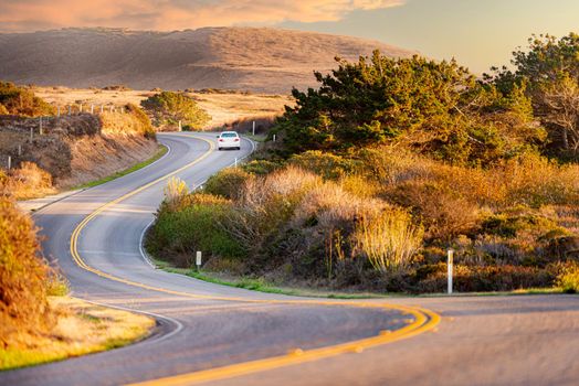 Car at highway, Big sur coast in California, United States of America. Mountains in background.