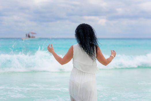 A woman on the beach looks at the horizon and walks along the beach. Mexico.