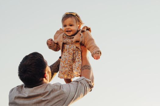 Daddy Lifting His Baby Daughter in Arms on Sky Background at Sunset, Happy Father's Day Concept