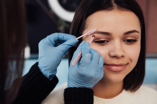 Close Up Female Master Combs Eyebrow to Young Woman, Process of Cleaning Procedure at Beauty Salon