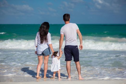 Parents with a small child walk on the beach and admire the horizon. Mexico..